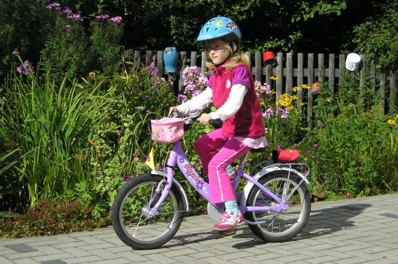 Ein Kind macht auf einem kleinen Puky-Fahrrad auf einem Gehweg ihre ersten &Uuml;bungen 