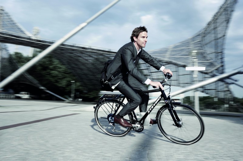 Ein Mann in einem Anzug flitzt mit einem E-Bike durch die Stadt