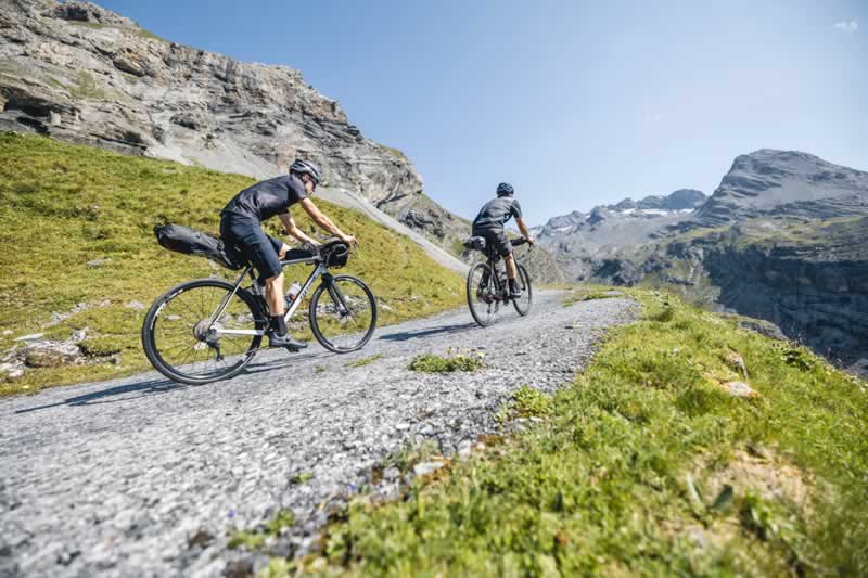 Zwei Personen fahren mit je einem Gravelbike einen Schotterweg nach oben